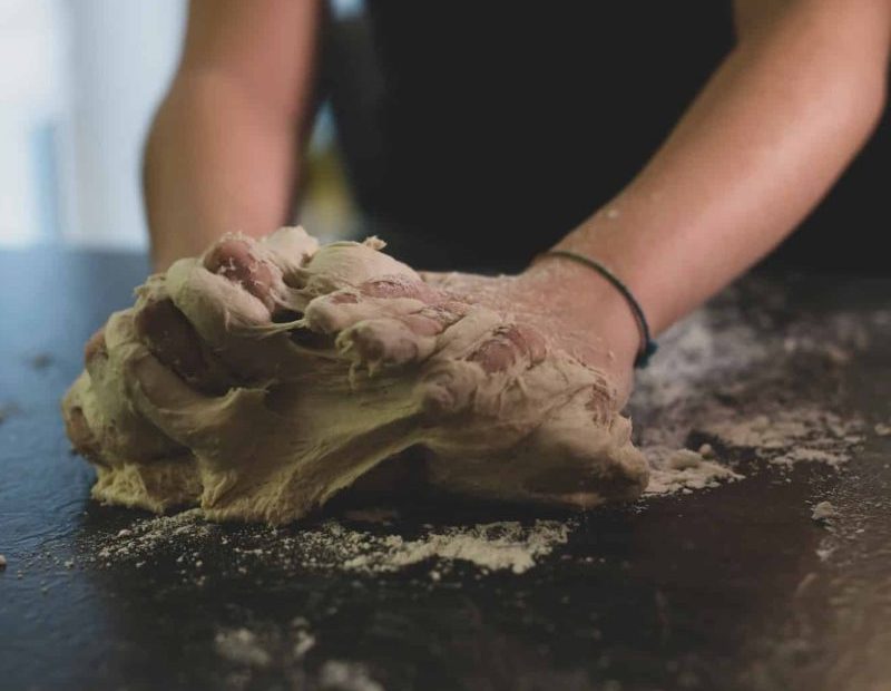 Hvordan elte pizzadeig. Dame som knar pizzadeig